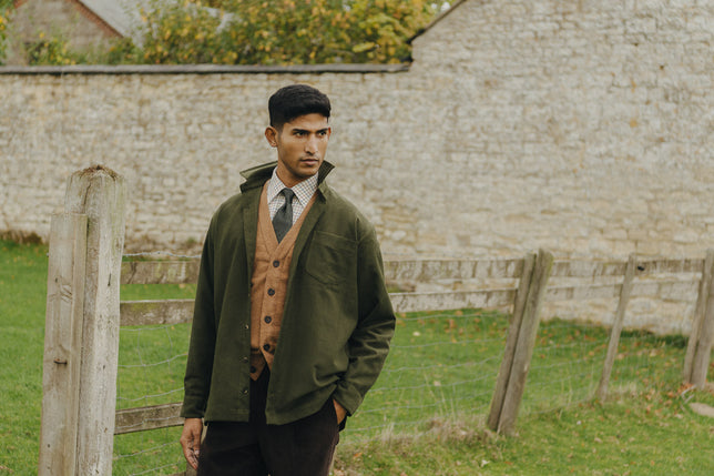 Man stood in garden wearing autumn knitwear and safari shirt