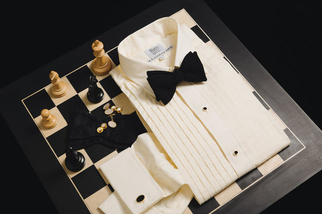 Cream silk pleated dress shirt laid on chess board