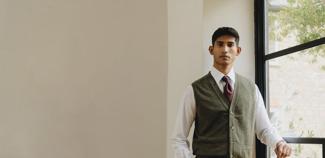 Man wearing olive green knitted vest with shirt and tie