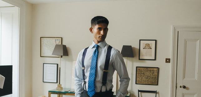 Man wearing blue shirt and navy coloured braces stood in home office