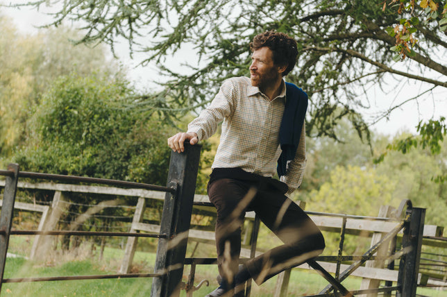 Man wearing checked shirt sat on fence outdoors
