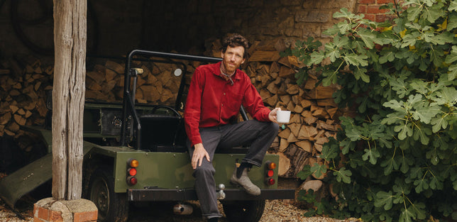 Male model wearing a red casual fit shirt sat in log store