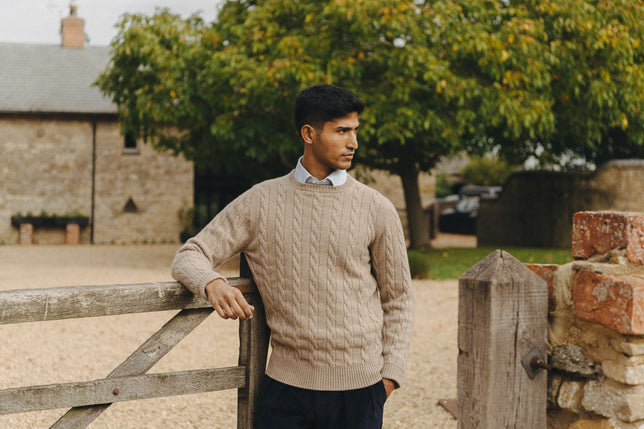 Man stood in garden wearing beige cable knit jumper