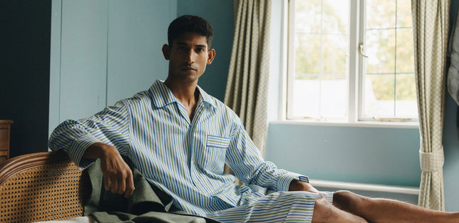 Male model laid on bed wearing a striped nightshirt