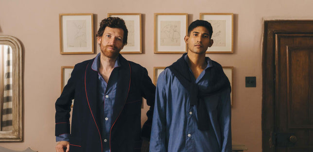 Two men stood in a bedroom in pyjamas and dressing gown