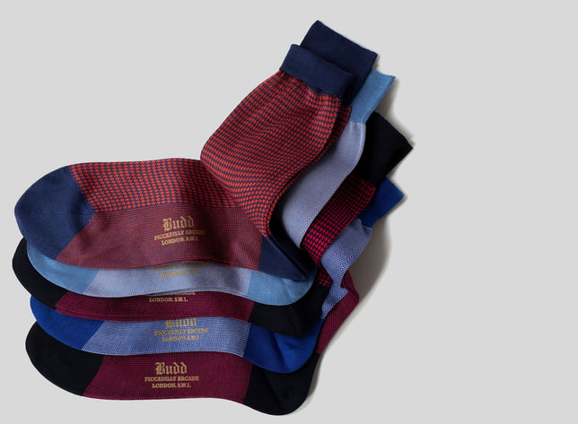 Set of blue and red socks on plain pale grey background