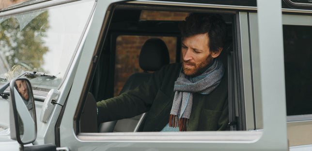 Man sat in car wearing scarf in grey