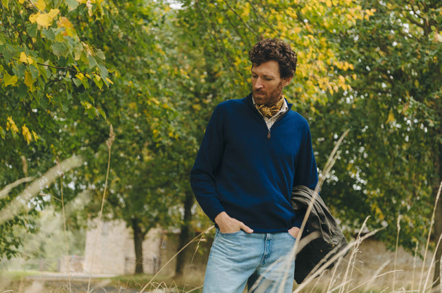 Model stood in garden wearing yellow neckerchief and navy zip up sweater