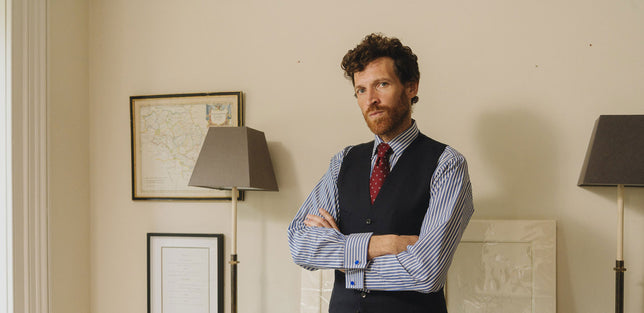 Male model wearing blue budd stripe shirt stood in a home office