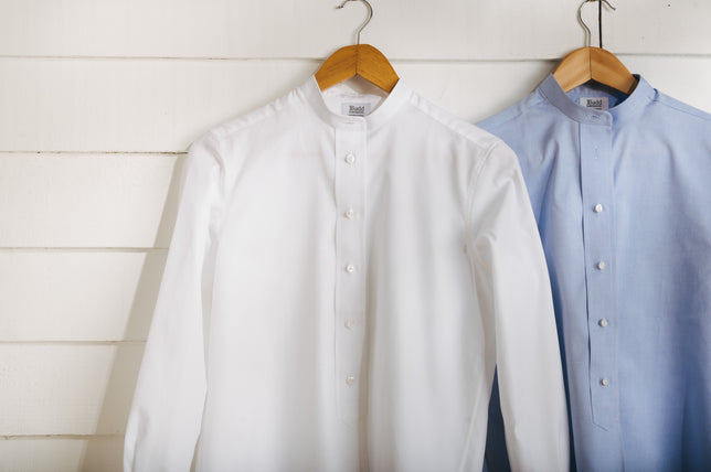 Womens white and blue shirt hung up on white washed wooden background