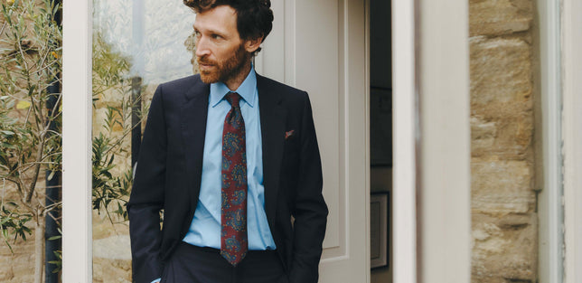 Male wearing blue shirt and paisley tie stood in doorway