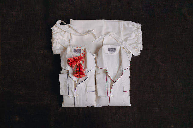 White pyjama sets laid flat with red paper christmas tree decorations laid on them