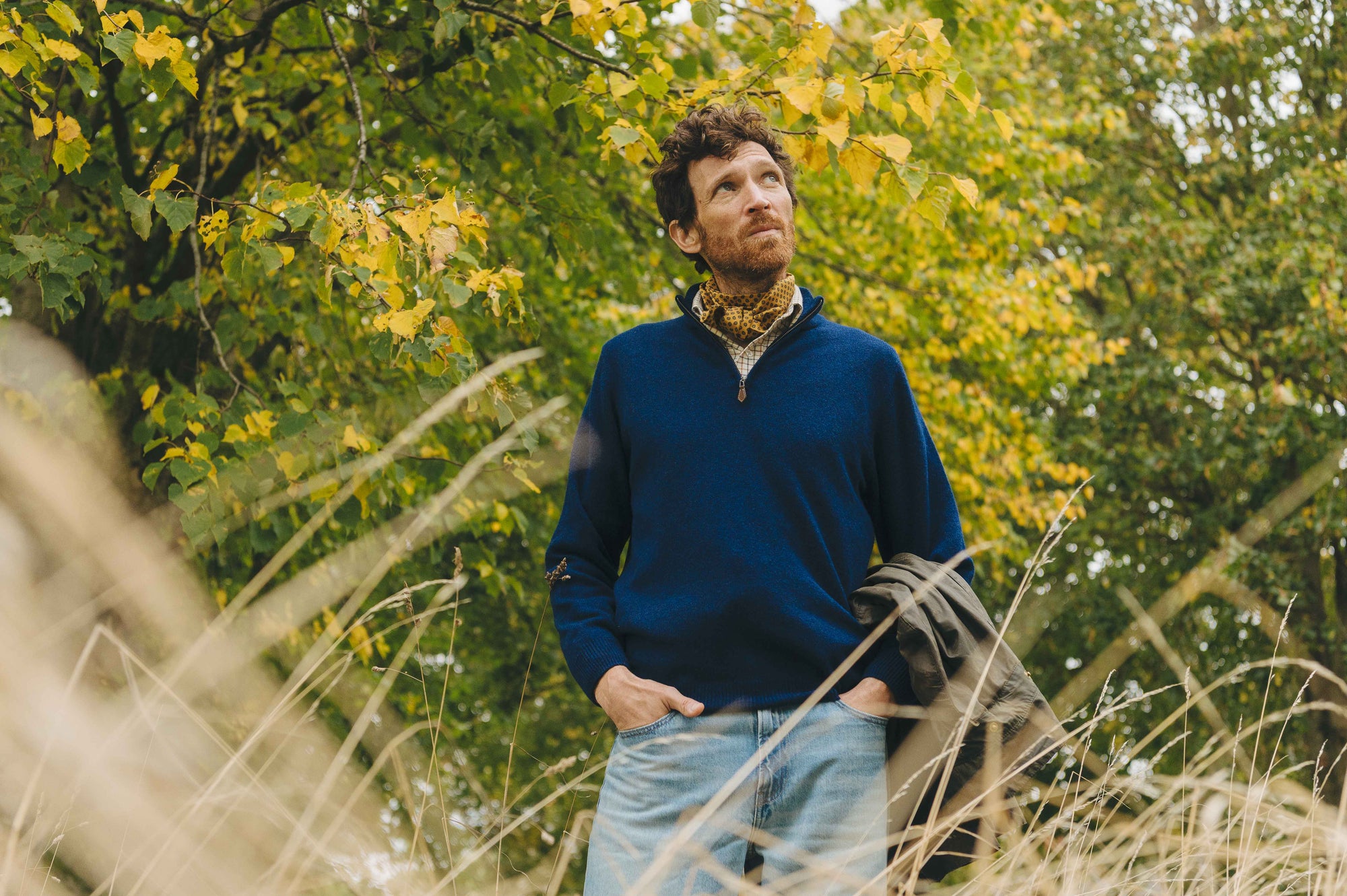 Man wearing blue quarter zip jumper against trees outdoor