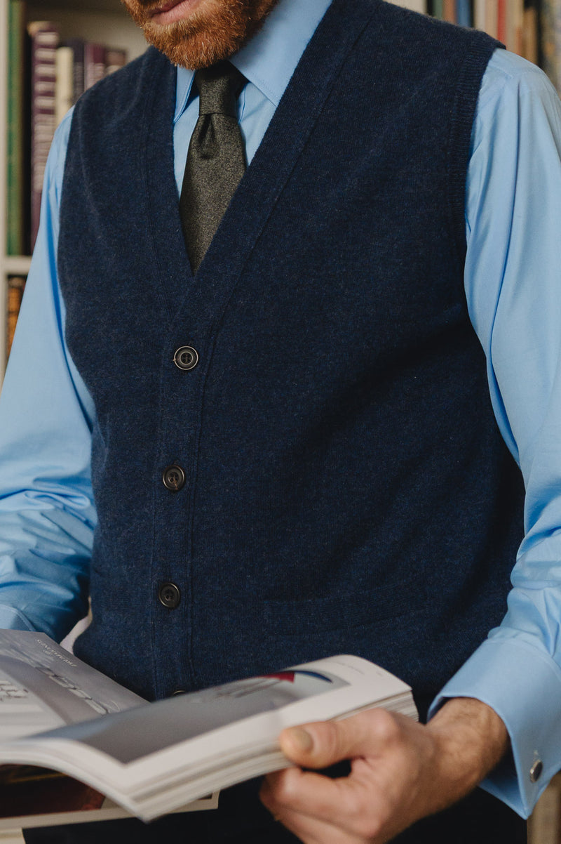 Navy knitted slipover vest on model reading book