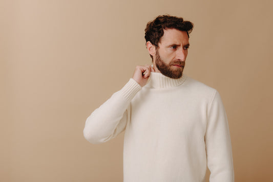 Cashmere white roll neck jumper on male model against cream background