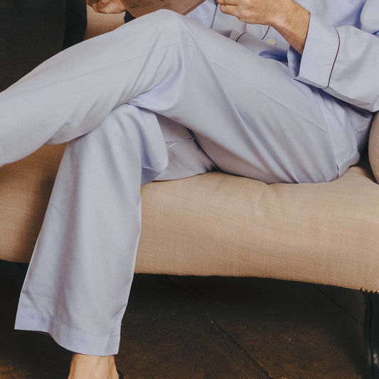 Person wearing light gray pants sitting on a beige couch.