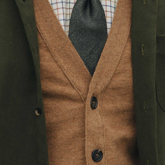 Brown knitted vest with buttons on a dark green coat background