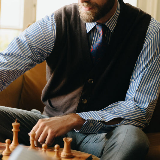 Detail of sleeveless cashmere cardigan in dark brown, seen on seated model