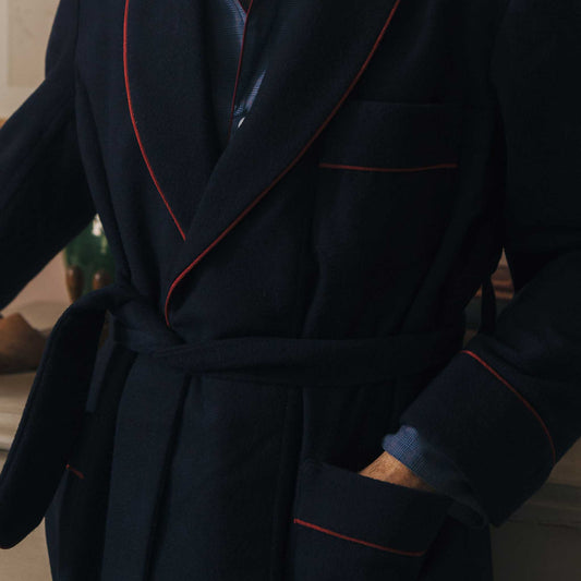 Dark blue dressing gown with red piping worn by a person indoors.