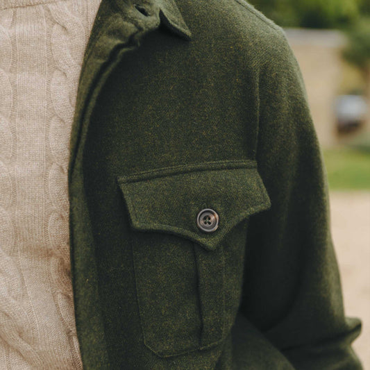 Detail pocket shot of man wearing green safari jacket and beige cable knit jumper