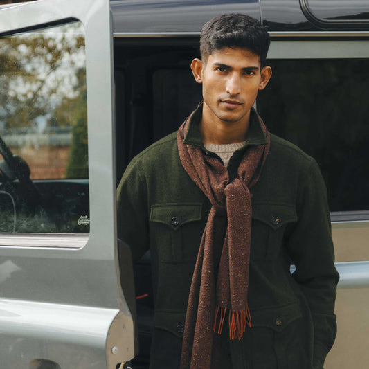 Man wearing green safari jacket and beige cable knit jumper with brown scarf