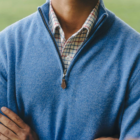 Close up neck detail of Male model stood in field wearing blue quarter zip jumper