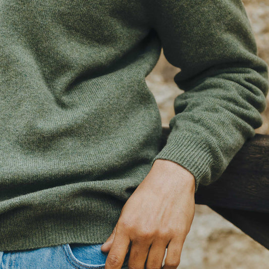 Close up cuff shot of male model wearing olive green quarter zip jumper stood outside