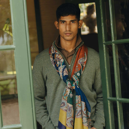 Man wearing a patterned scarf standing in front of a glass door.