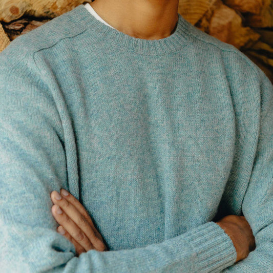 Person wearing a light blue sweater with a blurred background