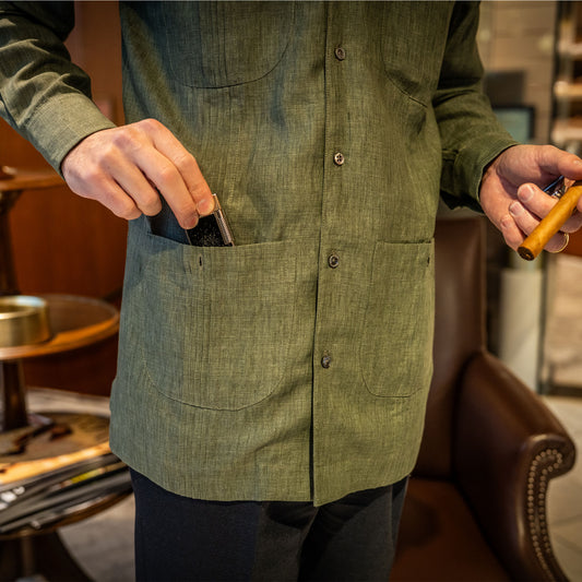 Person wearing a green shirt holding a lighter and a cigar in a casual setting.