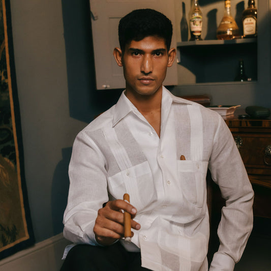 Man in a white shirt holding a cigar in an indoor setting