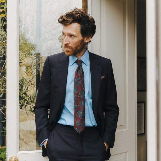Man in a suit with a patterned tie standing in a doorway.