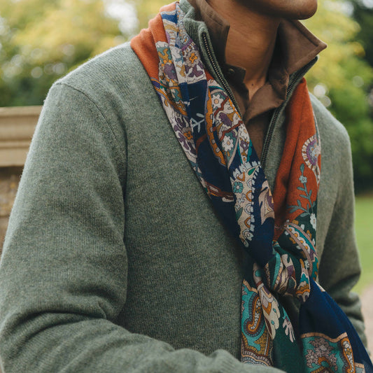 Person wearing a green sweater with a patterned scarf in an outdoor setting