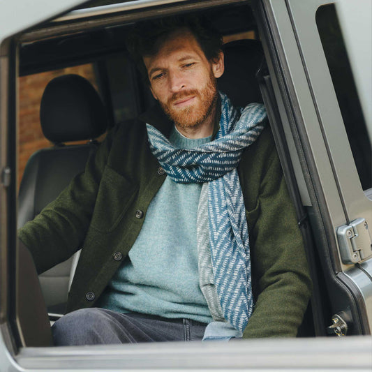 Man with a beard and scarf sitting in a car, looking out the window.