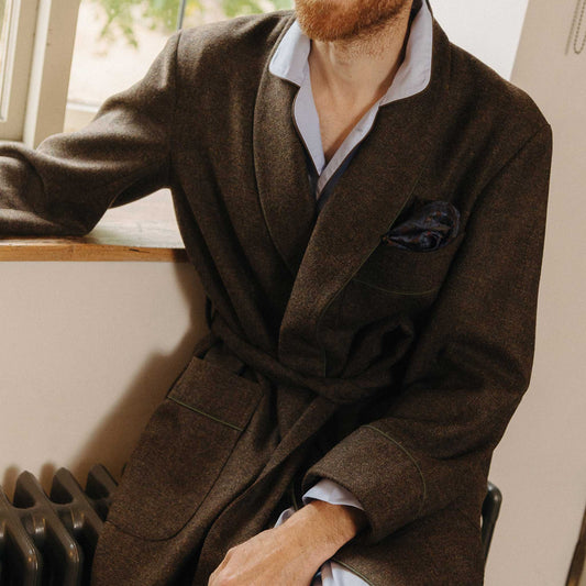 Male model wearing brown dressing gown sat on radiator