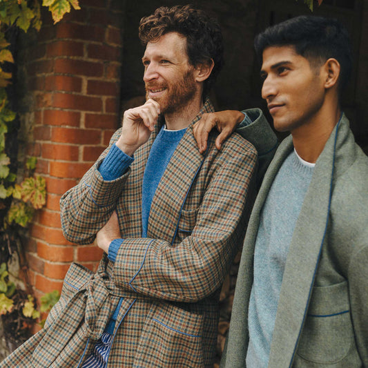 Two male models stood outside in log store wearing tweed dressing gowns and scarves