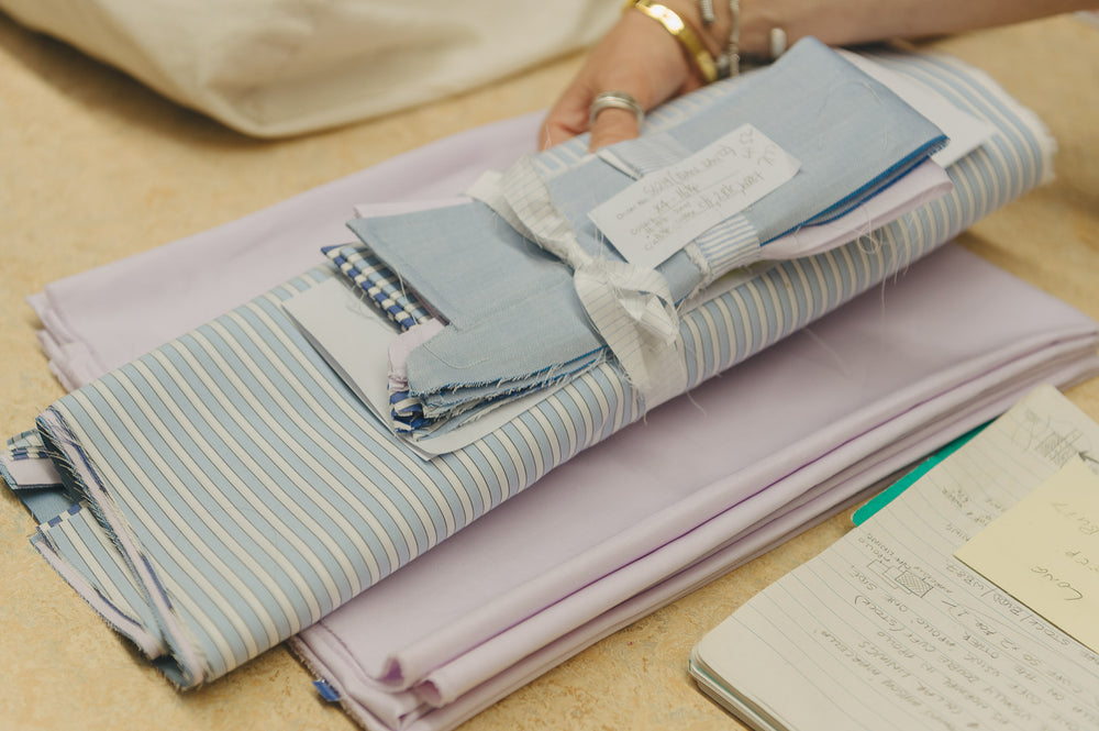 Stack of folded fabric swatches on a table with a notebook.