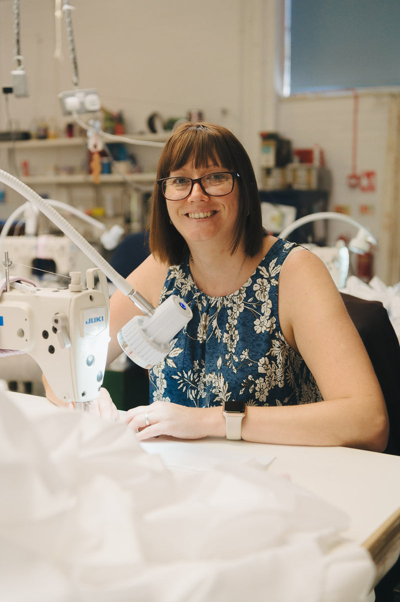 Lady machinist sat at sewing machine in shirt making workshop