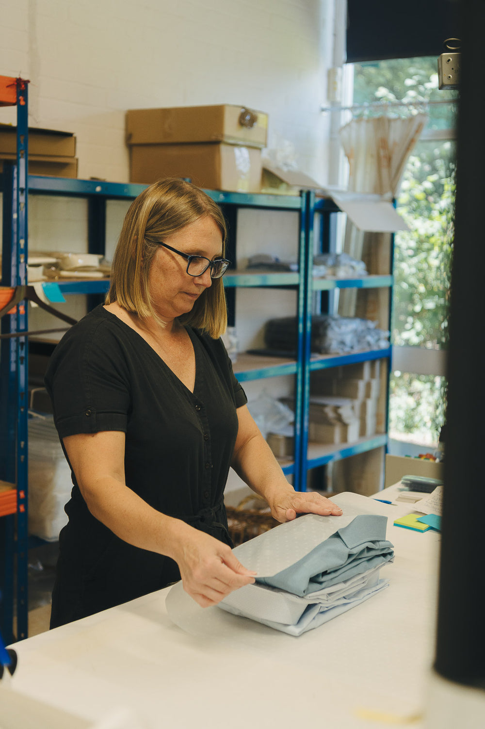 Woman folding fabric in a warehouse setting
