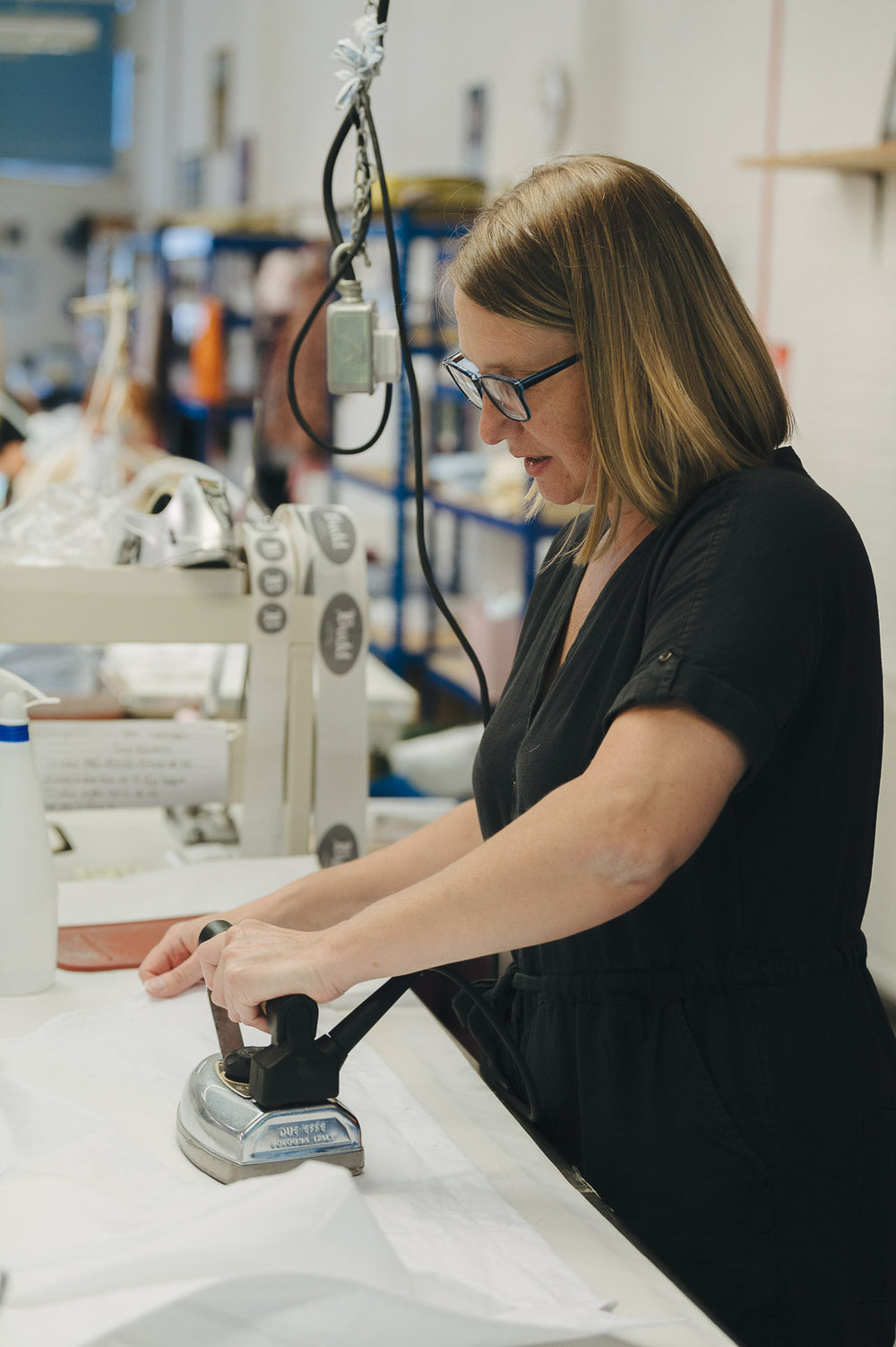 Lady in shirt making workroom pressing a shirt