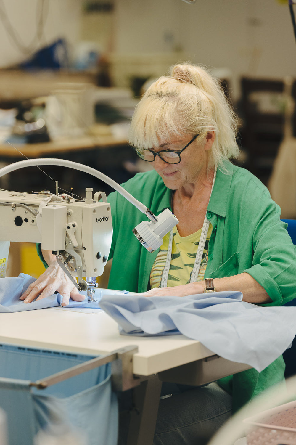Lady at a sewing machine working on a blue shirt
