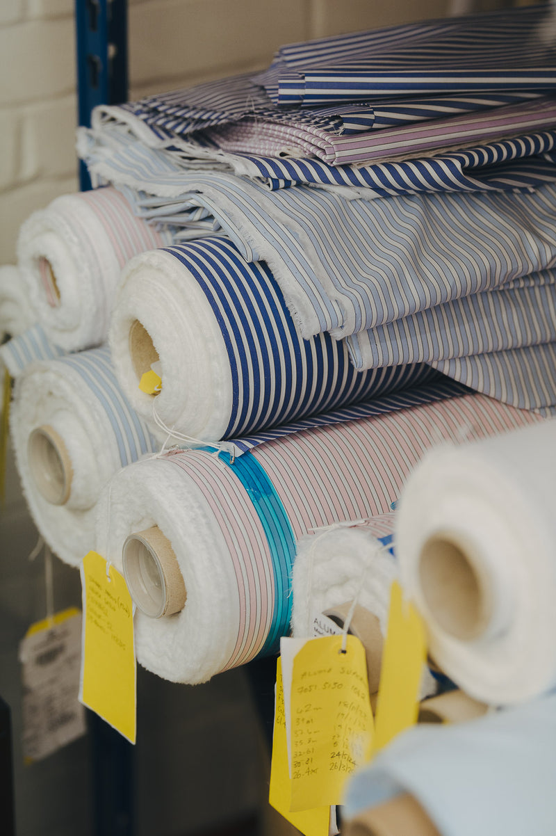 Rolls of fabric with striped patterns on a rack