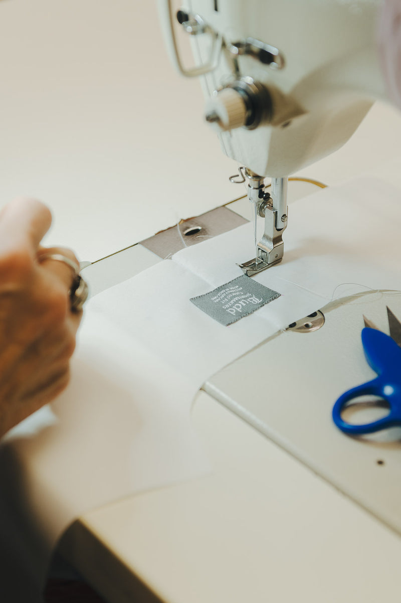 Person using a sewing machine with a close-up of the needle and thread.