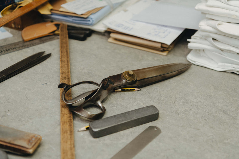 Scissors and other tools on a workbench with fabric and papers in the background