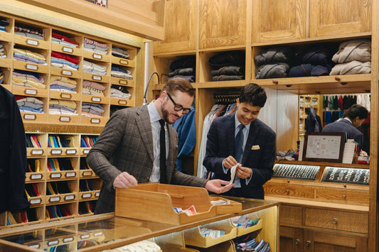 Retail manager and shop advisor in a clothing store looking at shirts in a display case.