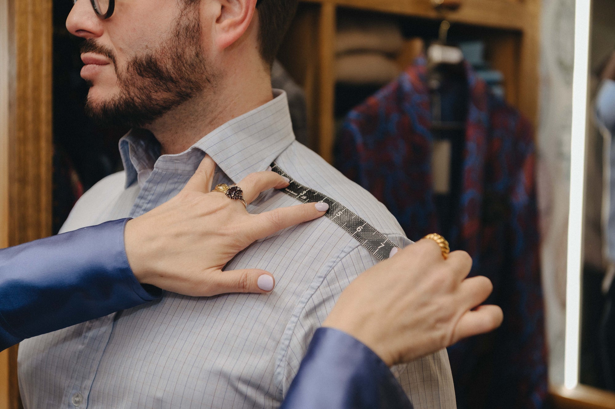 Person in store measuring a shirt for bespoke order