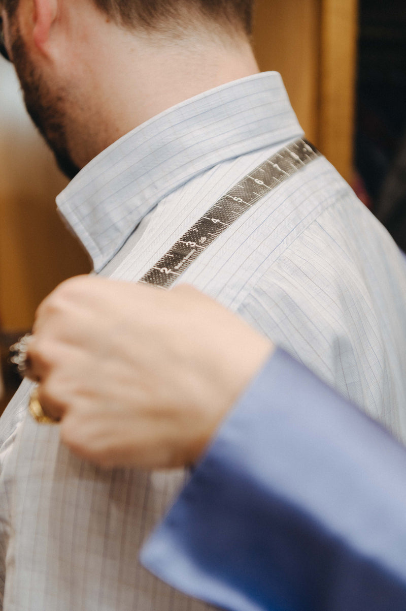 Person measuring a white shirt with a tape measure