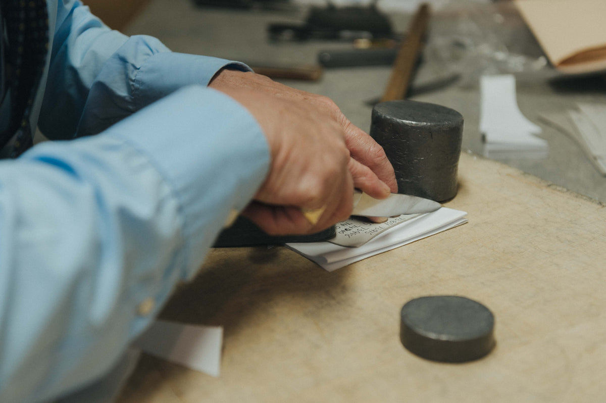 Man in blue shirt cutting a shirt with shirtmaking knife