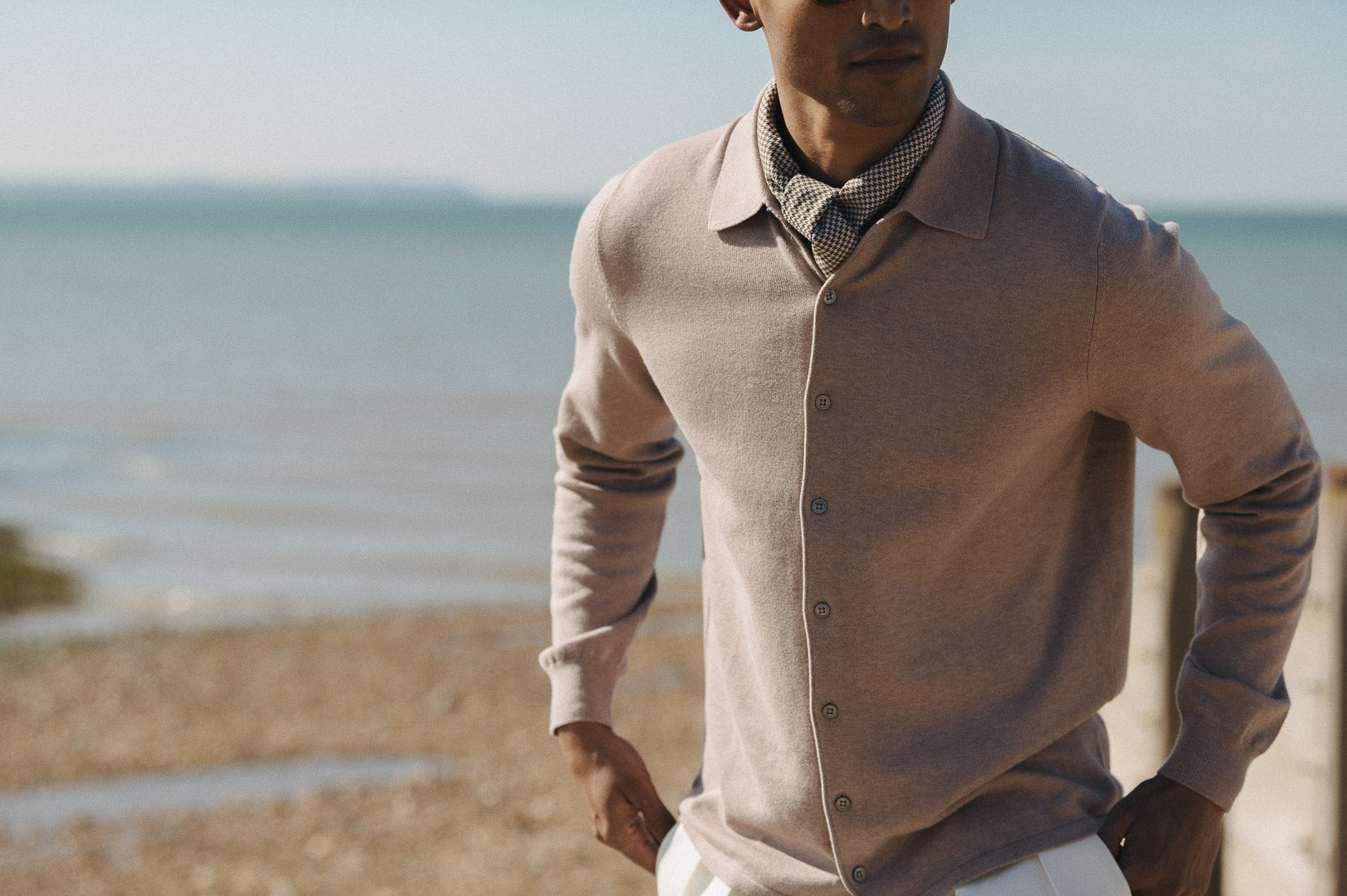 Man at the beach wearing a beige knitted shirt