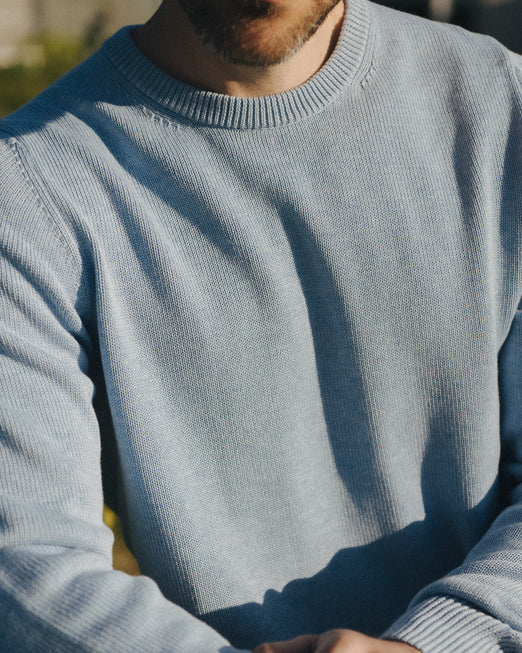 Man wearing a light blue sweater with a blurred background